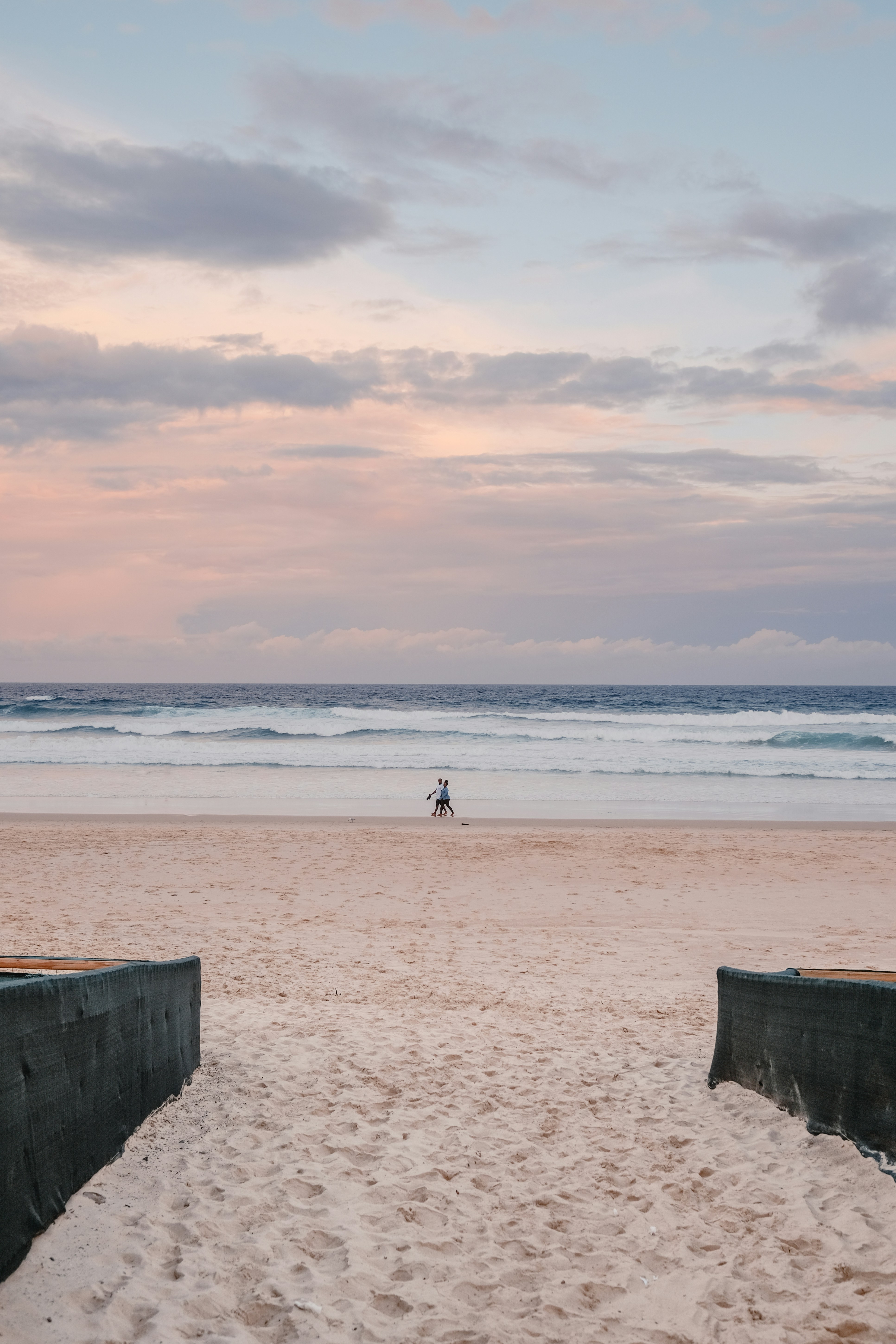 昼間に浜辺を歩く白いシャツを着た人