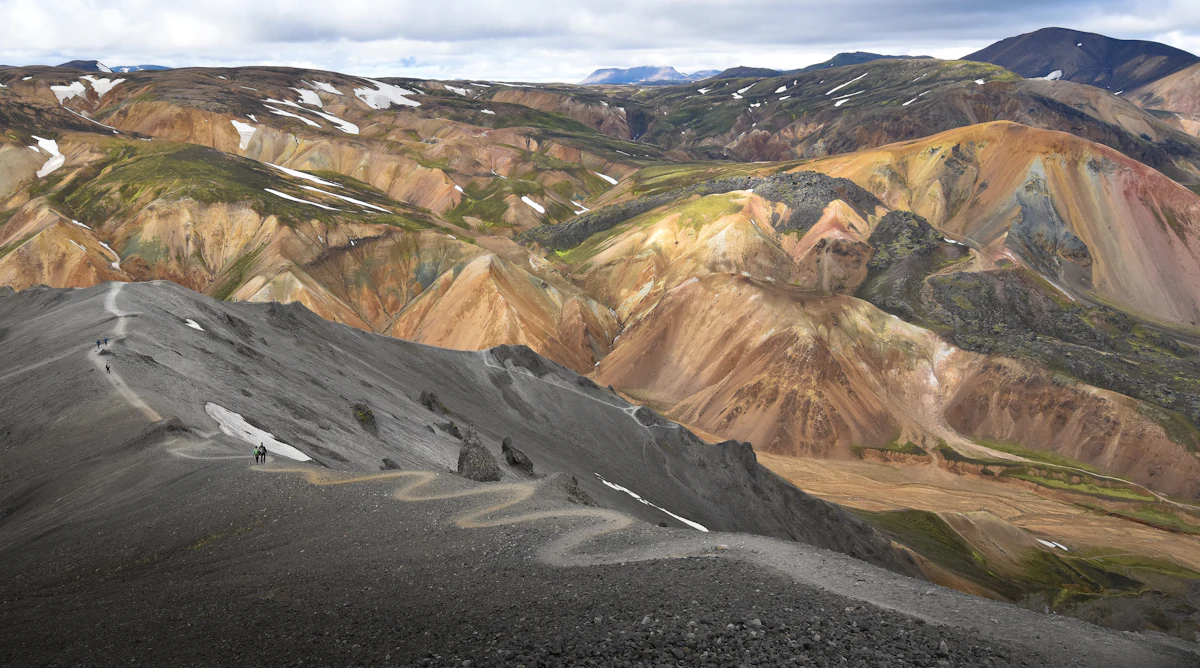 Rust, ochre and green hills at Landmannalaugar, with a path winding along a grey ridge