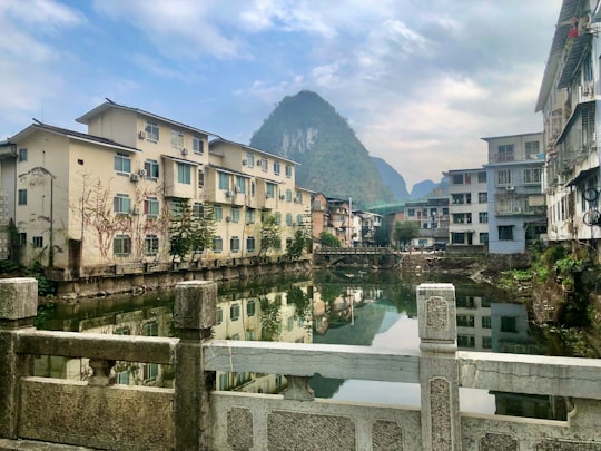 white concrete building near body of water during daytime in Yangshuo County China