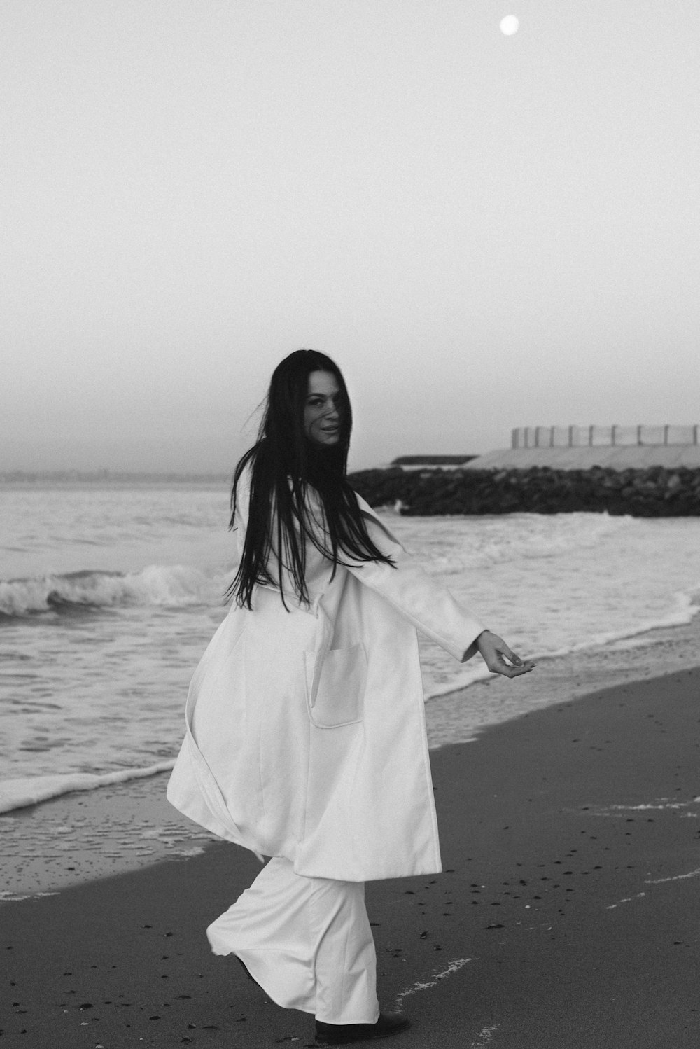 Frau in weißem Kleid tagsüber am Strand stehend