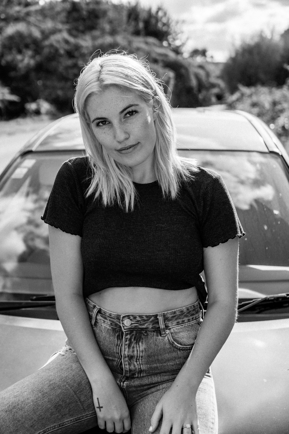 woman in black t-shirt and blue denim shorts sitting on car