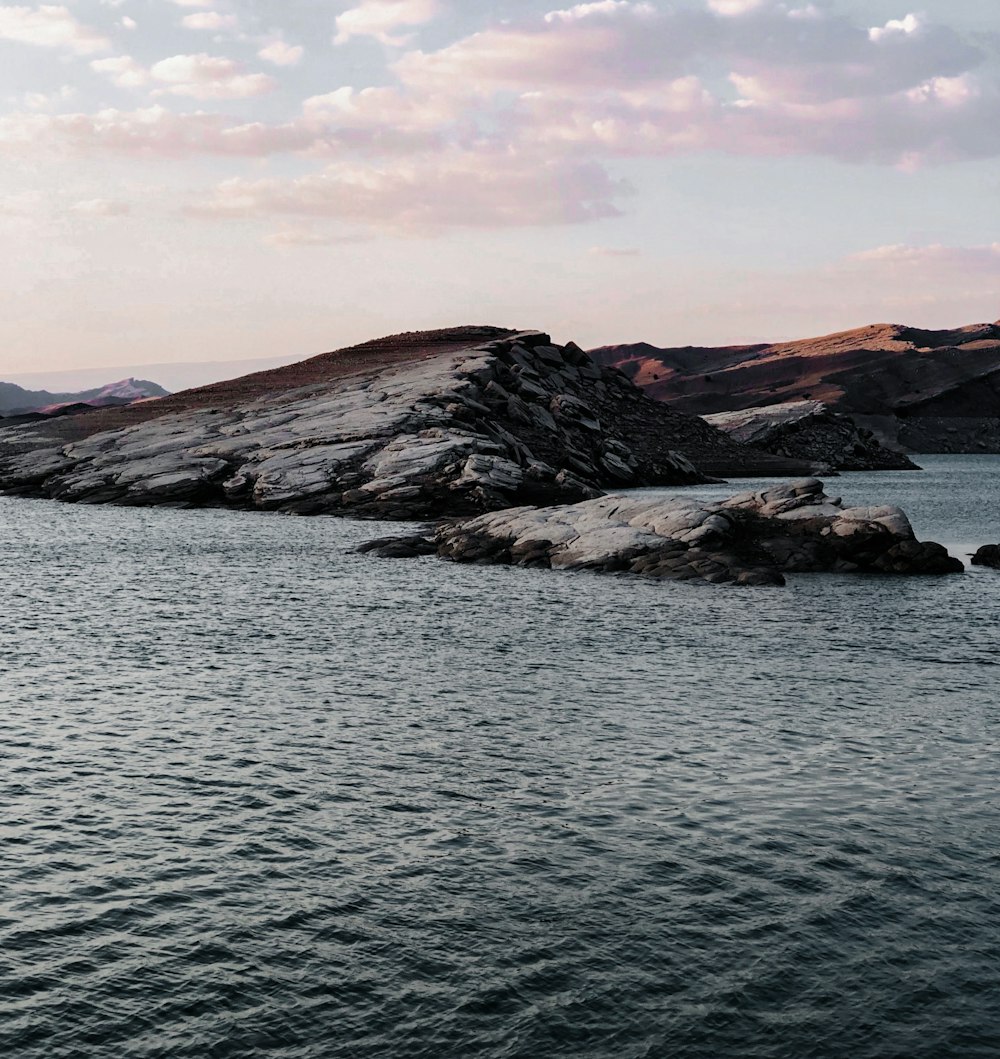 brown and black mountains beside body of water during daytime