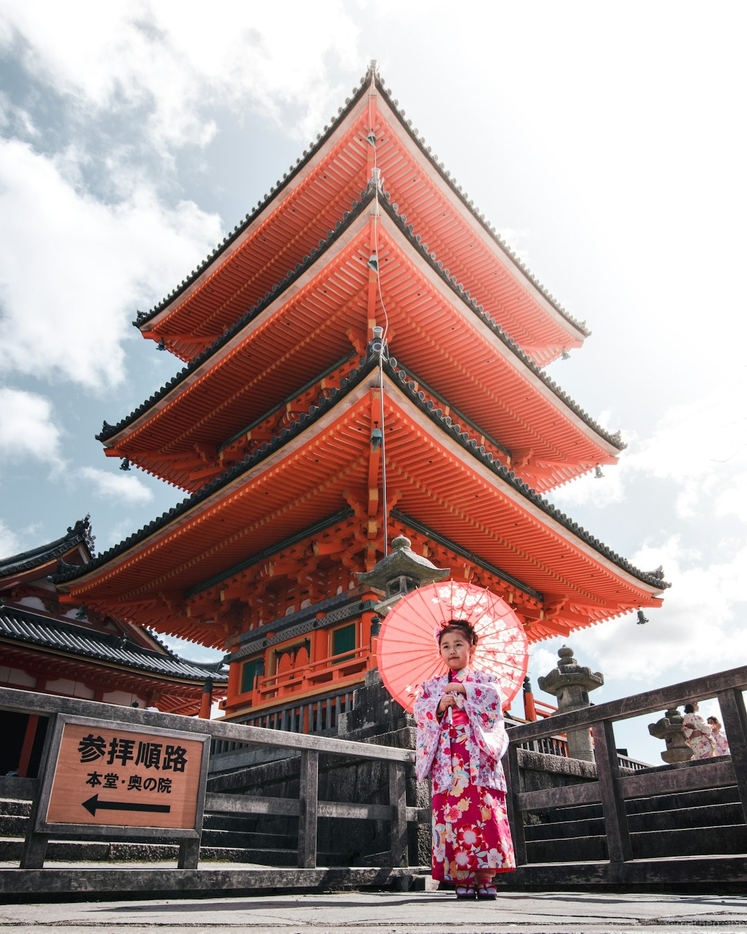 woman in pink and white floral dress standing near brown and white temple during daytime
