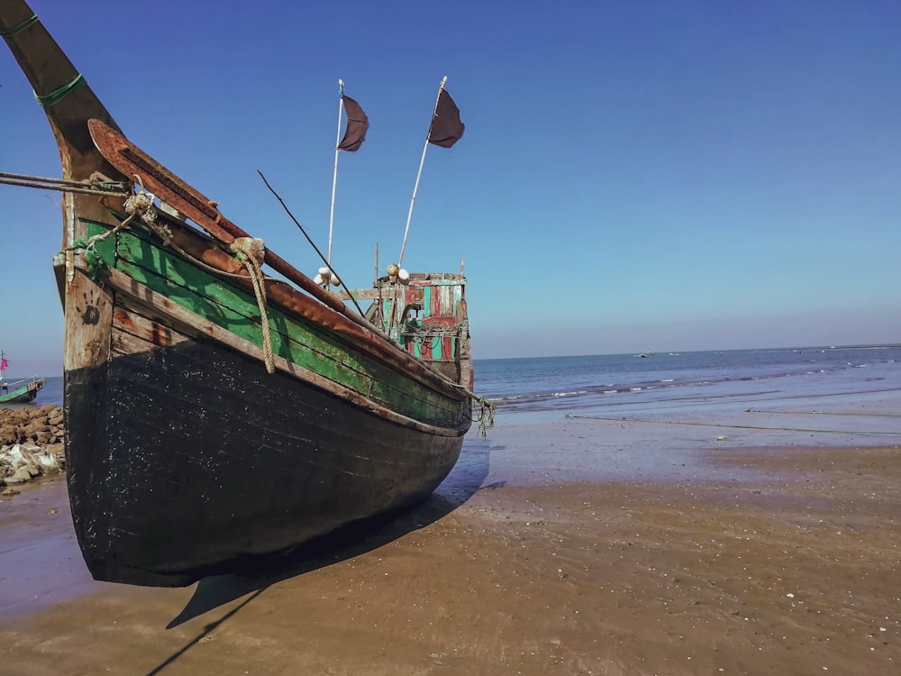 Barco verde y marrón en la playa durante el día