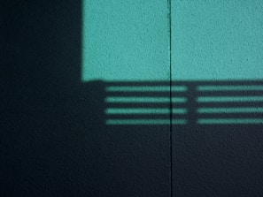 Modern geometric lines etched into a muted ochre wall, highlighted by deep blue shadows