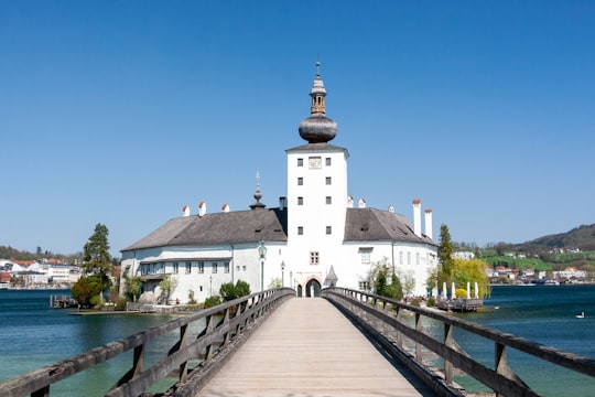 white and brown concrete building near body of water under blue sky during daytime in Schloss Ort Austria