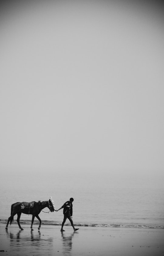 grayscale photo of man and woman sitting on rock formation in the middle of the sea in Kolkata India