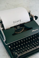 A vintage typewriter beside an open notebook filled with handwritten short stories in Greek.