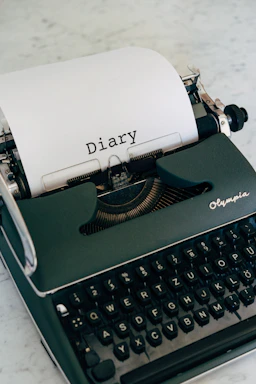 A vintage typewriter with a sheet of paper showing the title 'It Happened on the DMZ' resting on a wooden desk.