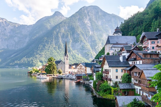 white and brown concrete house near body of water and mountain during daytime in Hallstatt Austria Austria