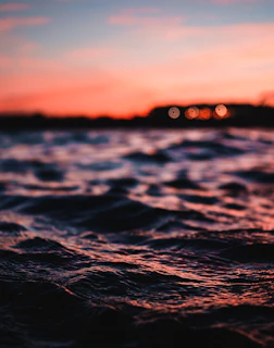 Sunset over the ocean with floating sensors measuring water quality, glowing softly in twilight.