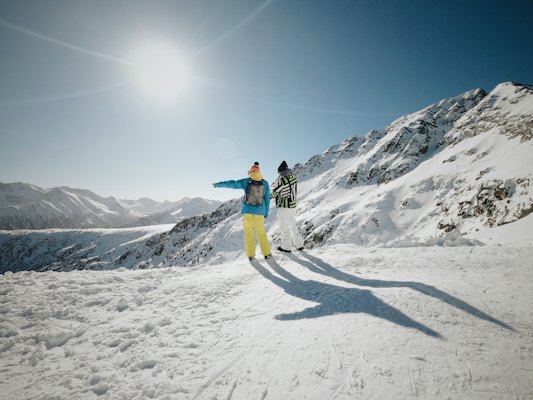 Woman in blue jacket and yellow pants standing on snow covered ground during daytime — Bansko, Bulgaria