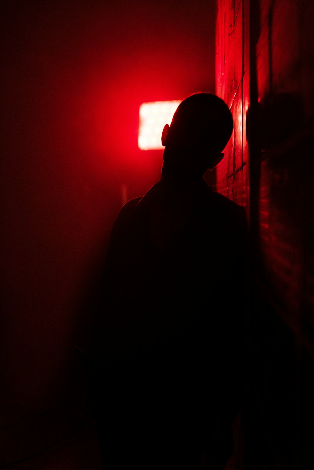 man in black shirt standing near red light