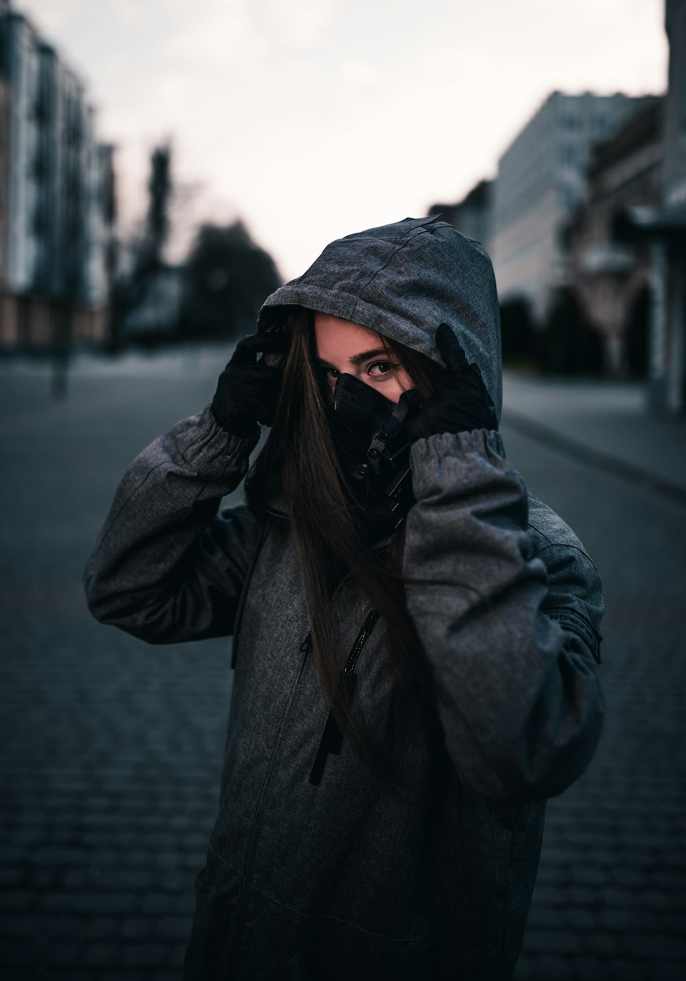 person in black hoodie standing on sidewalk during daytime