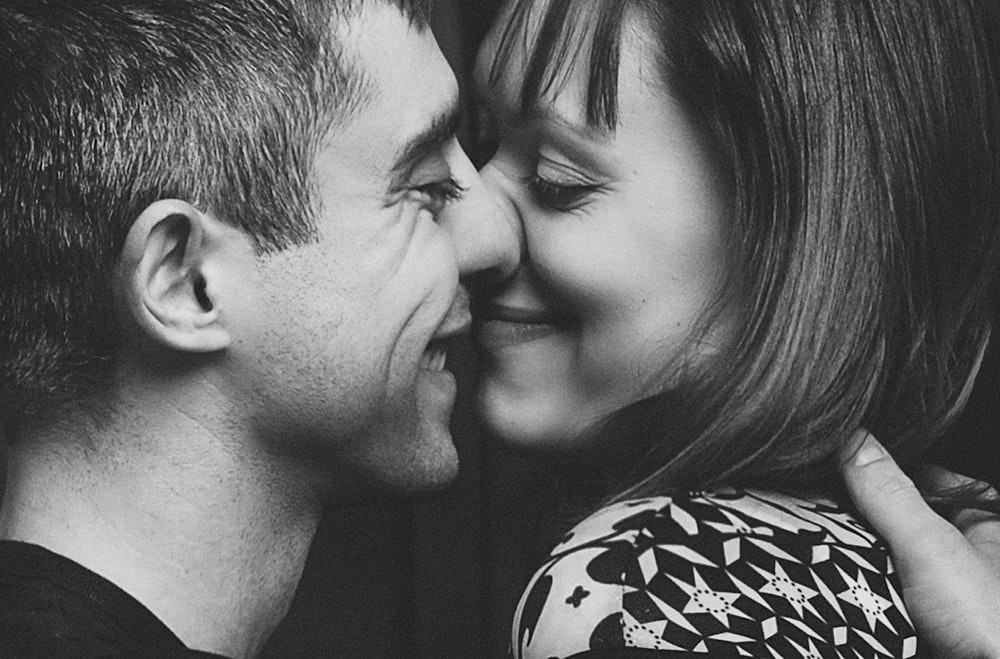 grayscale photo of man and woman kissing