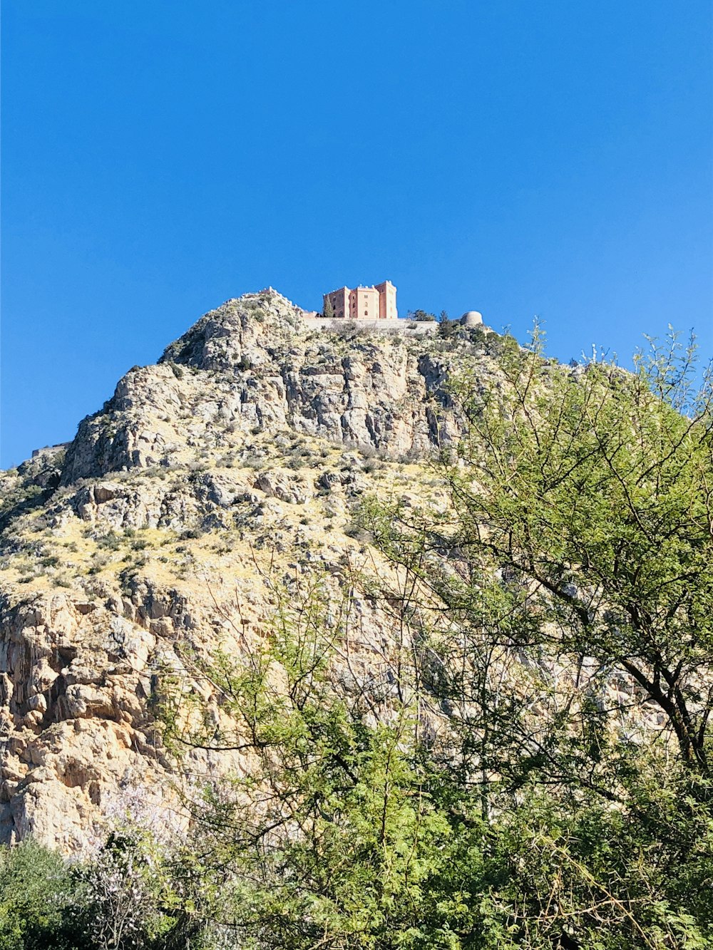 brown concrete building on top of gray rocky mountain under blue sky during daytime