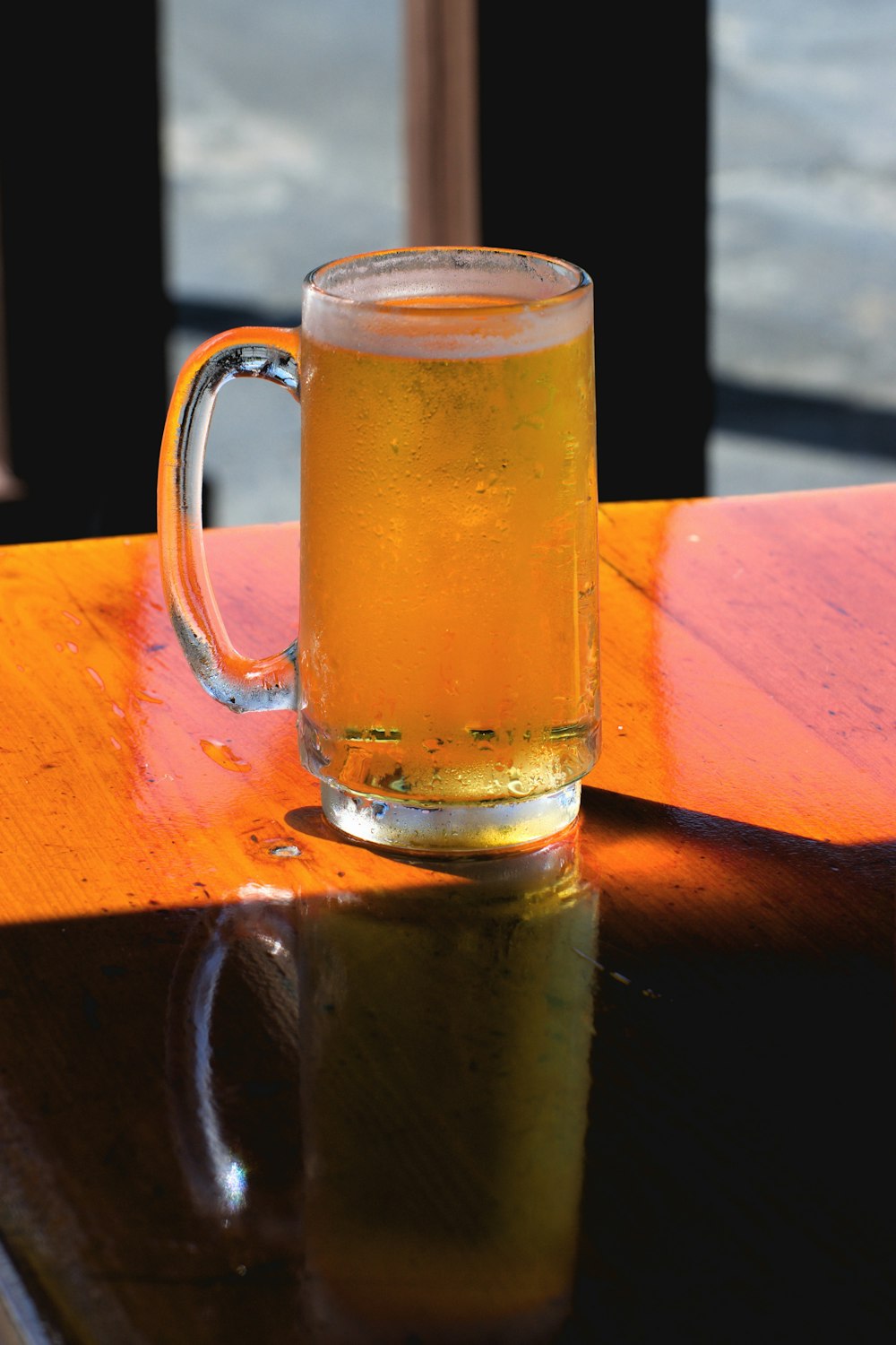 Chope de bière en verre transparent sur table en bois marron