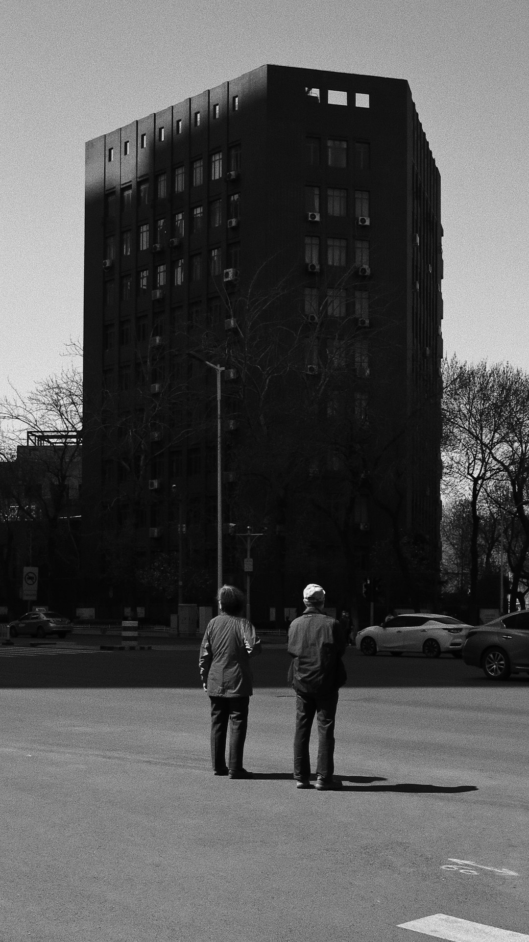 grayscale photo of man and woman walking on street