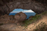 The famous Hercules Cave opening shaped like Africa, framing a stunning view of the sea beyond.