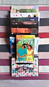 Stack of colorful books and notes beside a computer keyboard.