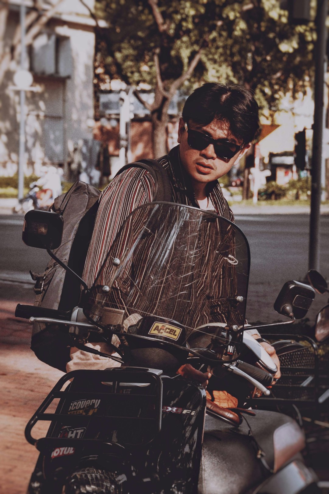 man in black and white striped shirt wearing black sunglasses sitting on motorcycle