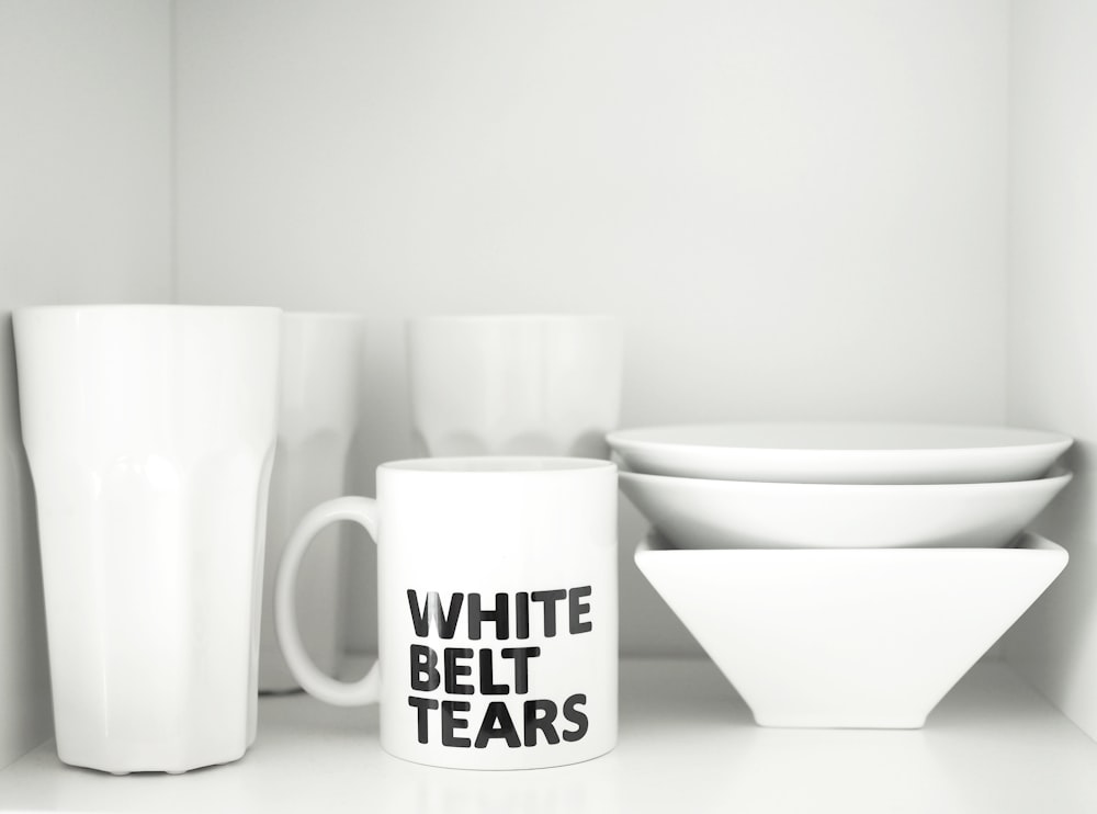 Tasse en céramique blanche à côté d’un bol en céramique blanche