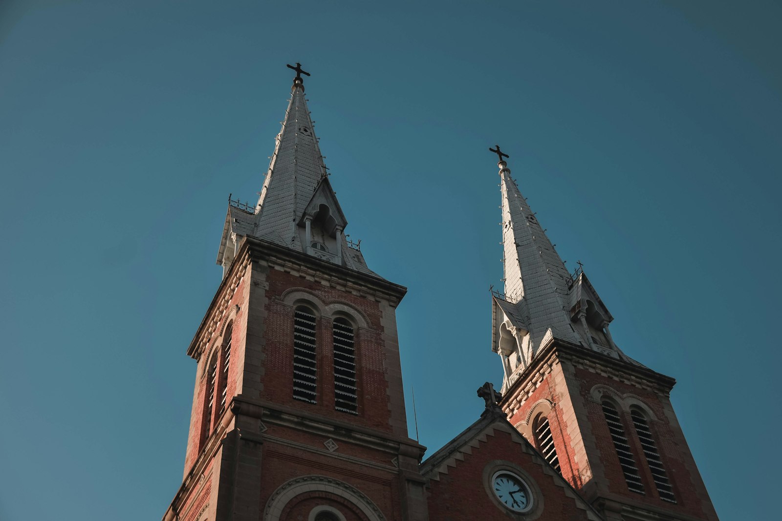 The twin red-brick spires of Saigon's Notre-Dame Cathedral against a deep blue sky