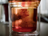 A close-up of deep red bromine liquid flowing in a laboratory glass container under bright light.