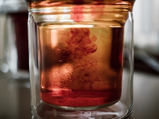 Close-up of a transparent redox flow battery tank showing the vibrant liquid electrolyte inside.