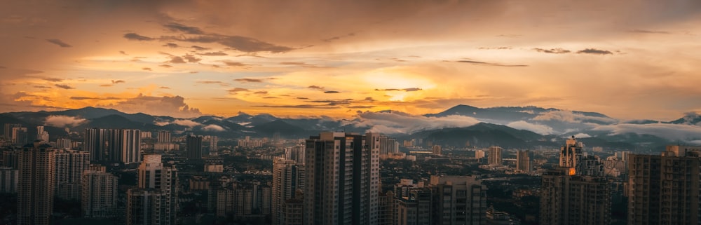 city skyline under orange and white cloudy sky during sunset