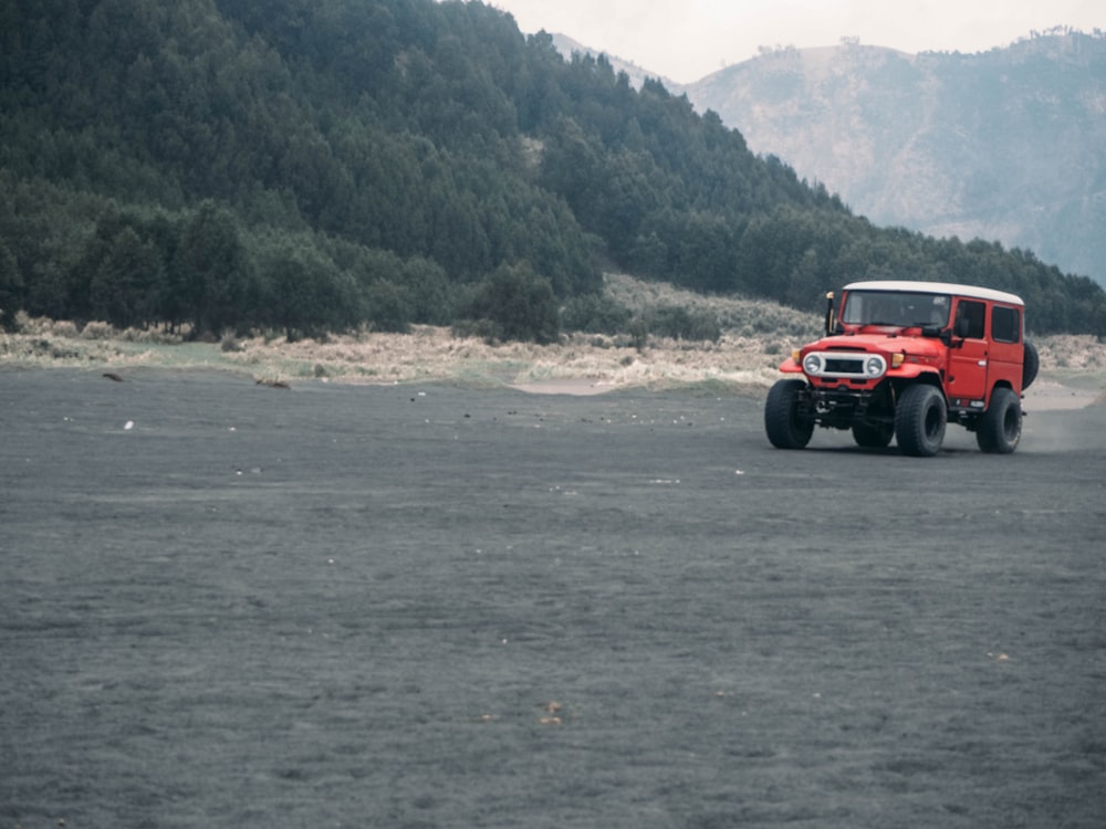 red and black jeep wrangler on gray sand during daytime