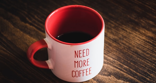 red and white ceramic mug on brown wooden table