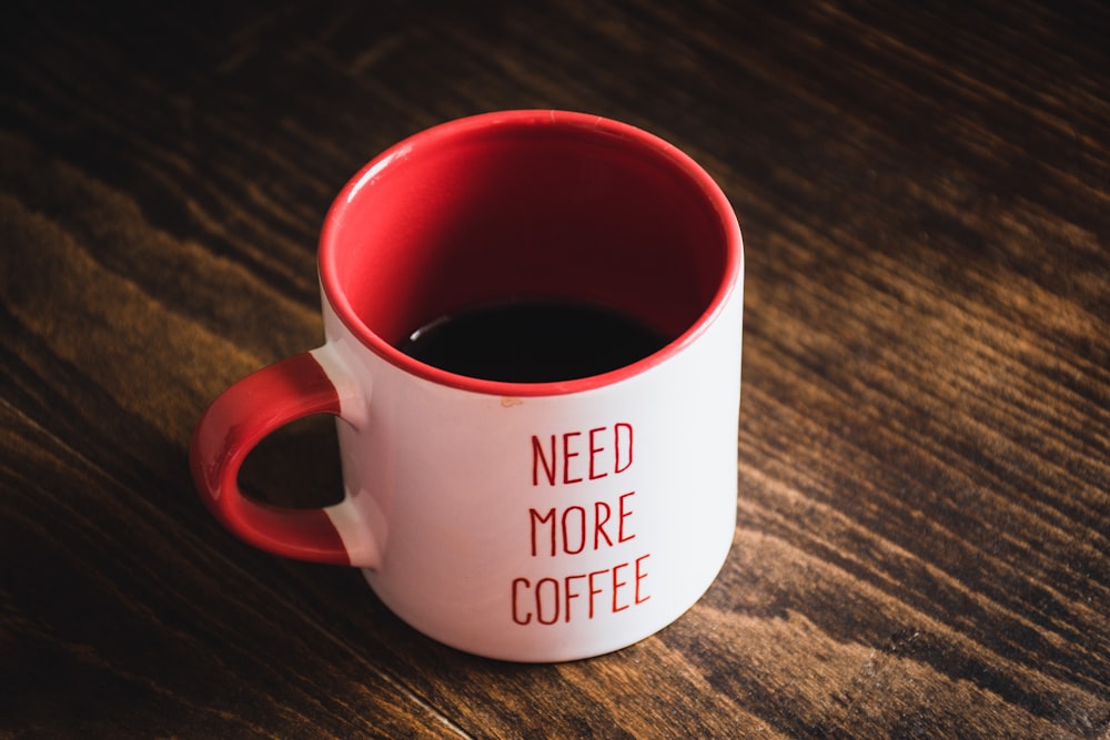 caneca de cerâmica vermelha e branca na mesa de madeira marrom