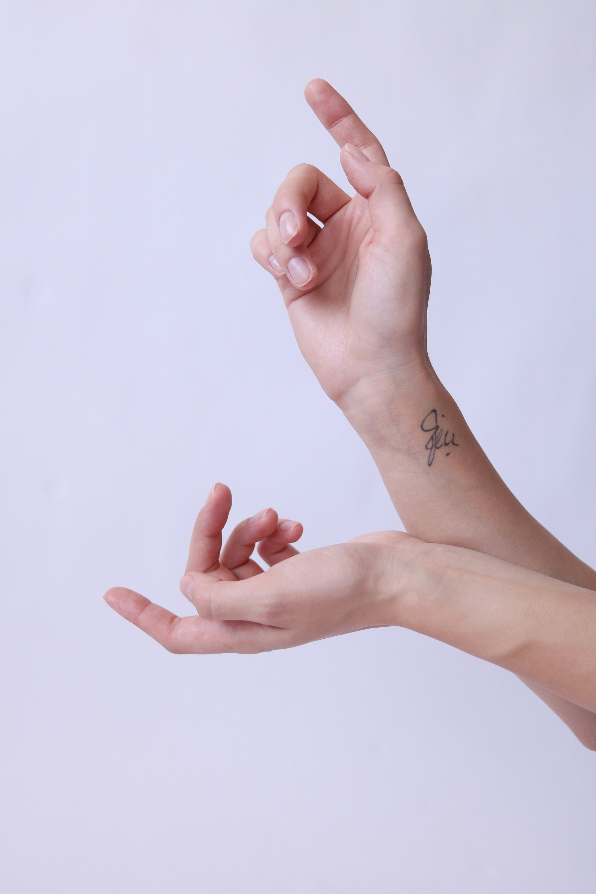 two hands in front of a mauve background