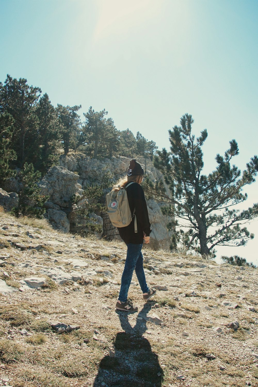 woman in black jacket and blue denim jeans standing on rocky ground during daytime