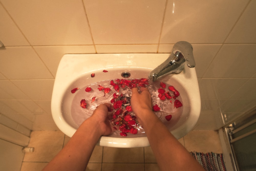 person holding white ceramic sink with stainless steel faucet