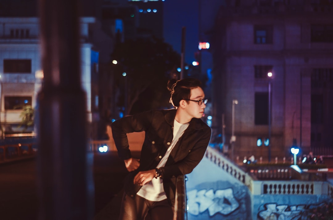 woman in black blazer and brown sunglasses standing on street during night time