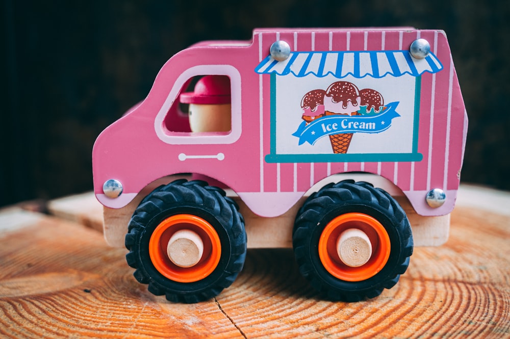 Foto Um caminhão de brinquedo rosa sentado em cima de um toco de árvore –  Imagem de Máquina grátis no Unsplash