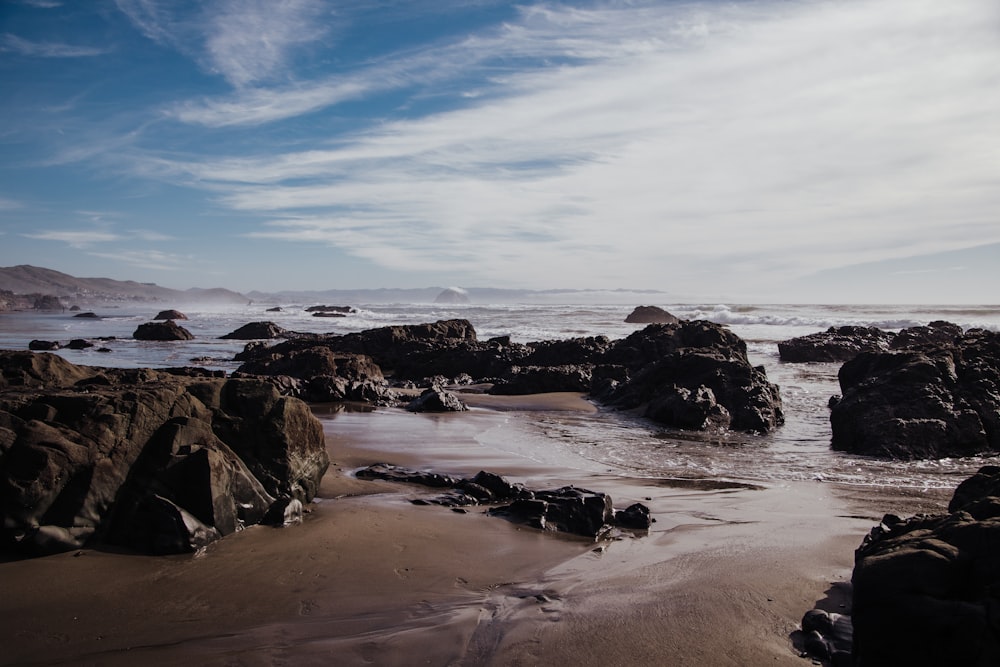 black rock formation on sea shore during daytime