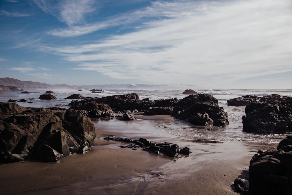 formazione rocciosa nera sulla riva del mare durante il giorno