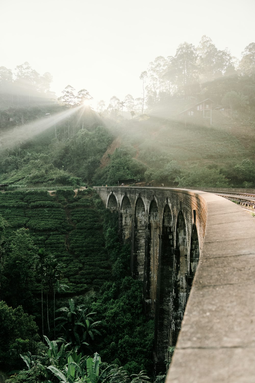 brown concrete bridge over green mountains during daytime