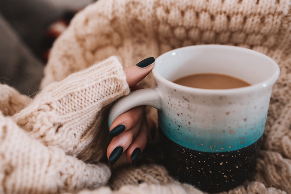 person holding blue ceramic mug with coffee