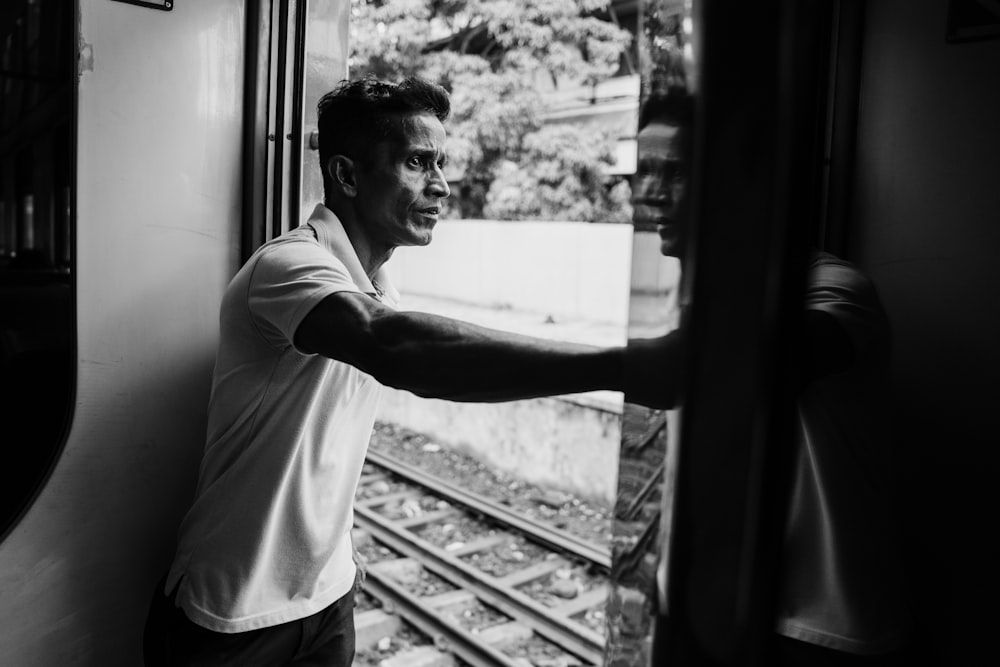 man in white t-shirt standing in front of window