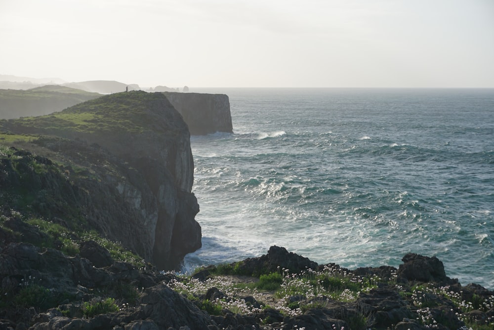 green and brown rock formation beside sea during daytime