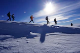 Group of friends hiking with Caserne sunglasses, smiling under a bright blue sky.