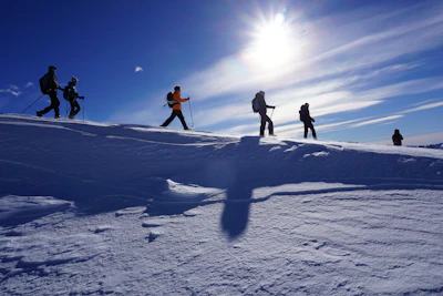 Group of friends hiking with Caserne sunglasses, smiling under a bright blue sky.