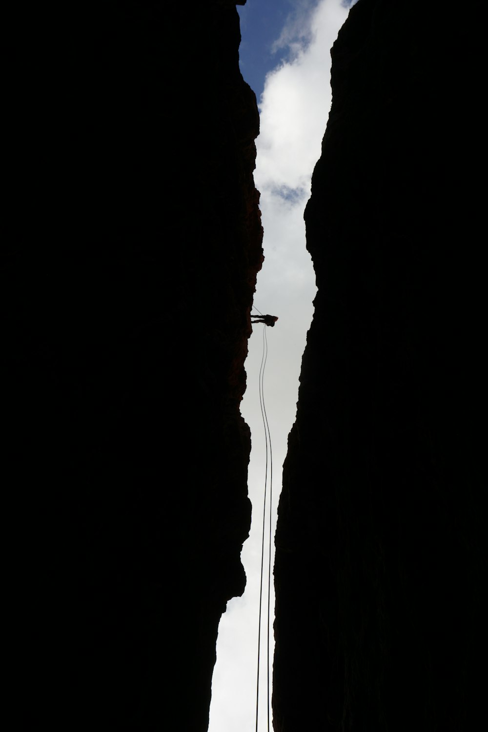 silhouette of person standing on rock formation during daytime