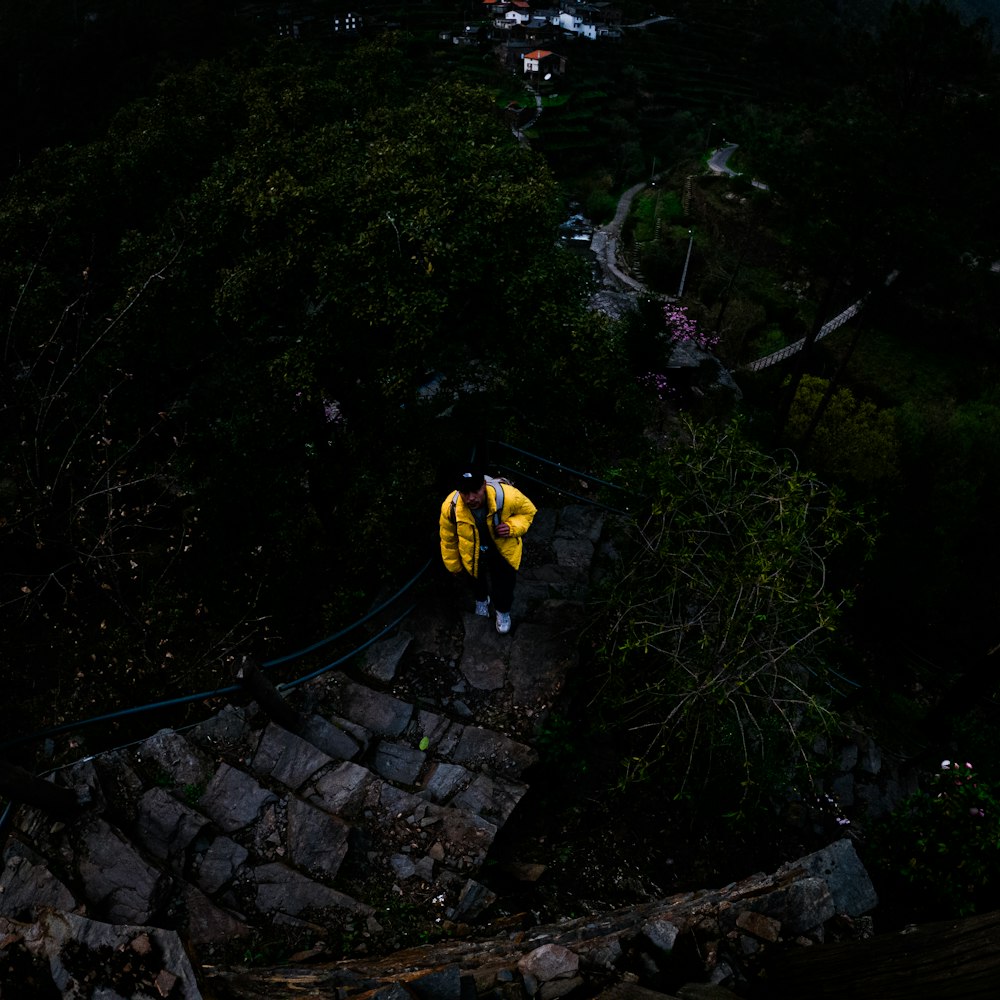 man in yellow jacket and black pants walking on brown concrete bridge