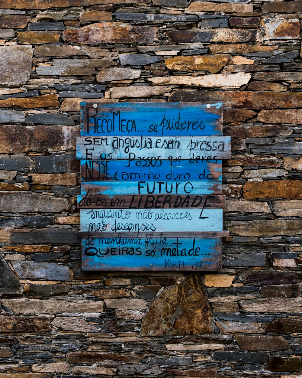 blue and white quote board mounted on brown brick wall