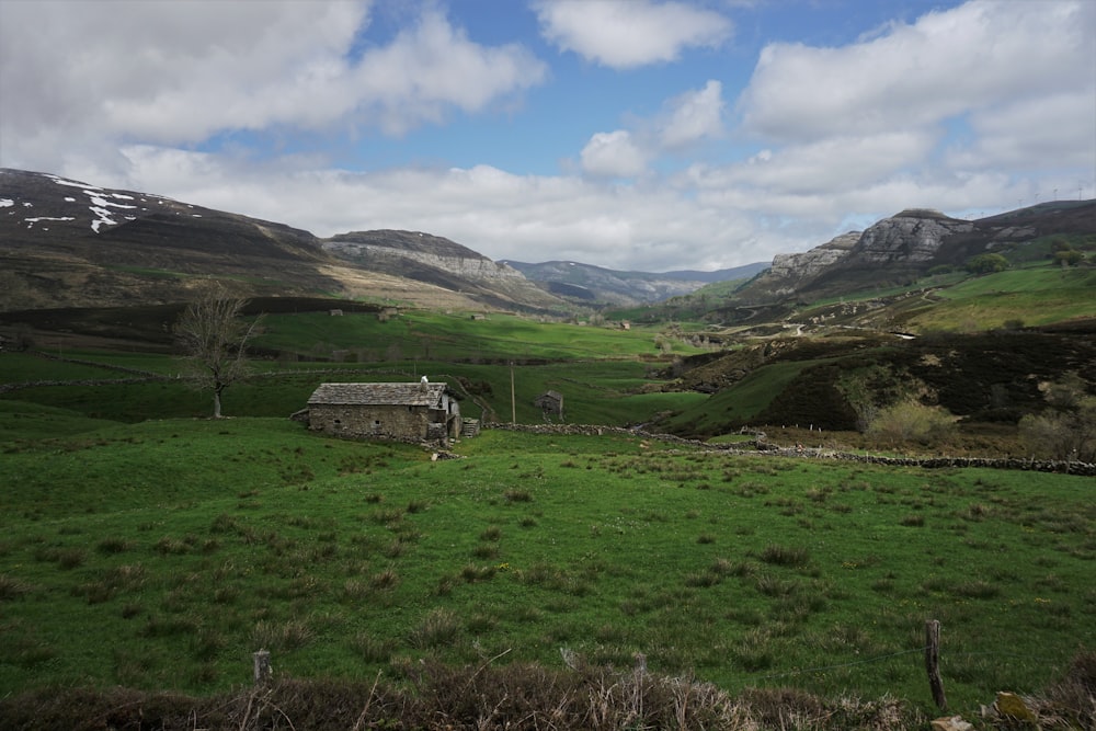 green grass field near green mountains under blue sky during daytime